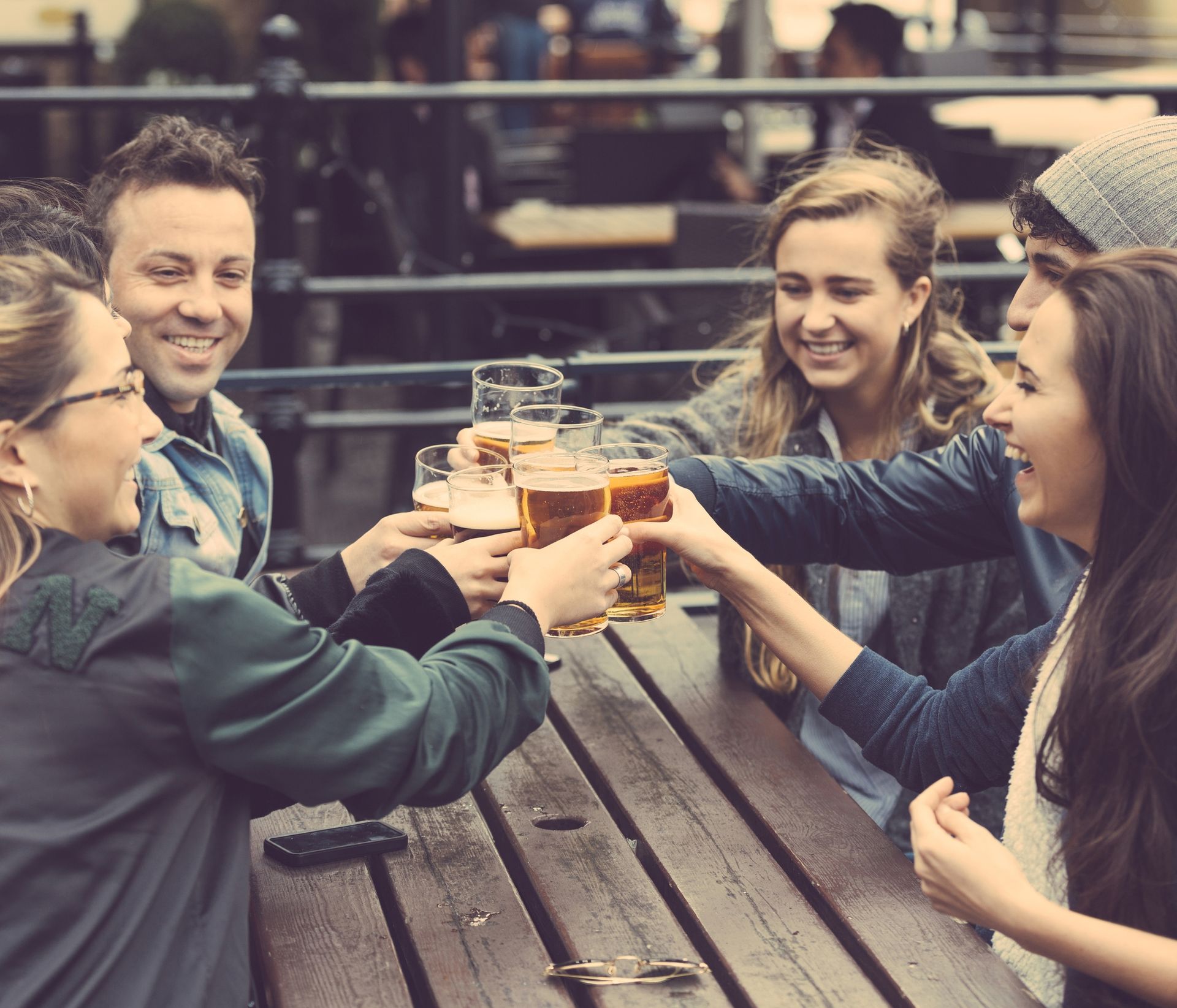 group of friends drinking beer at a picnic table