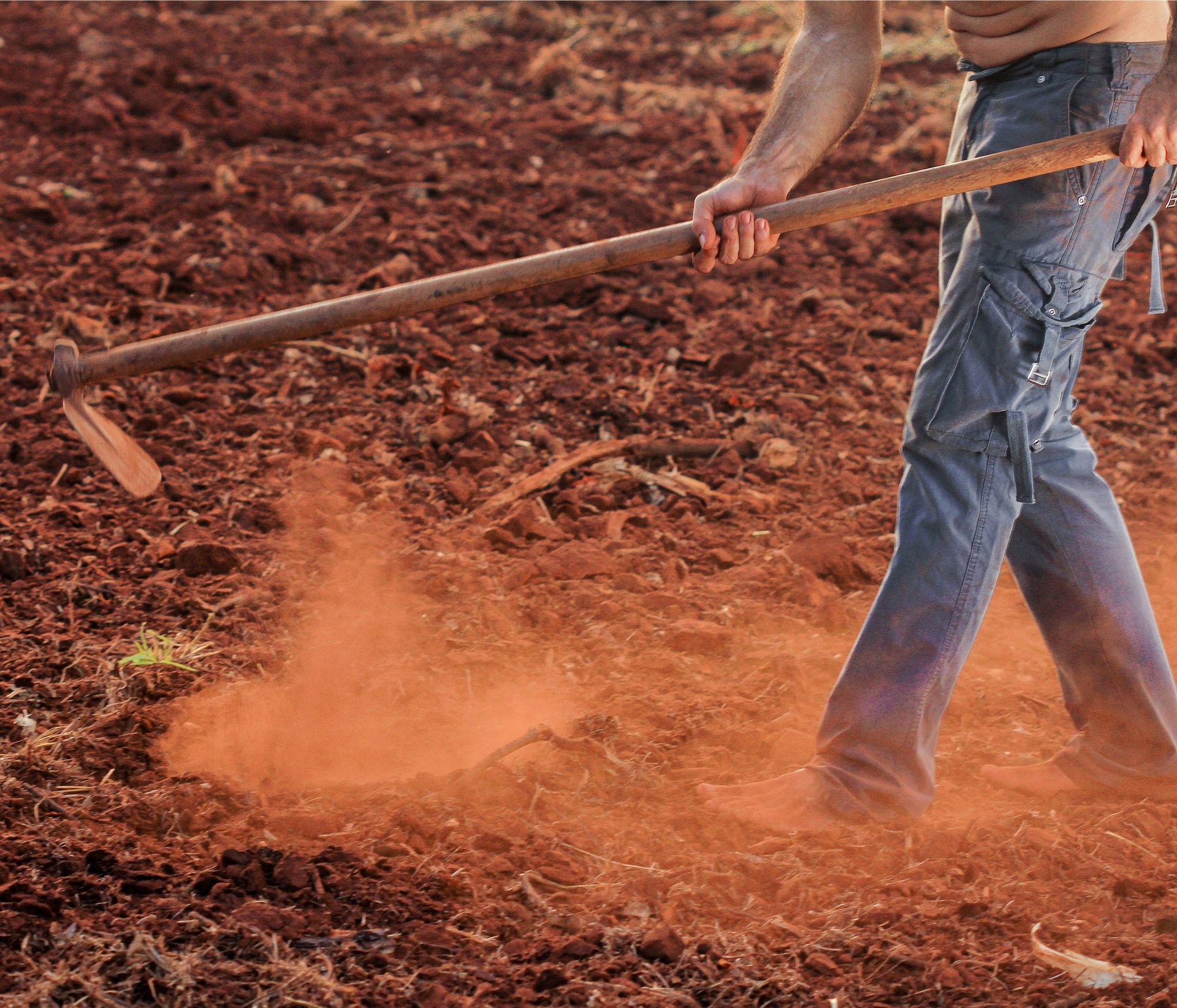 A man holding a hoe in a dry field